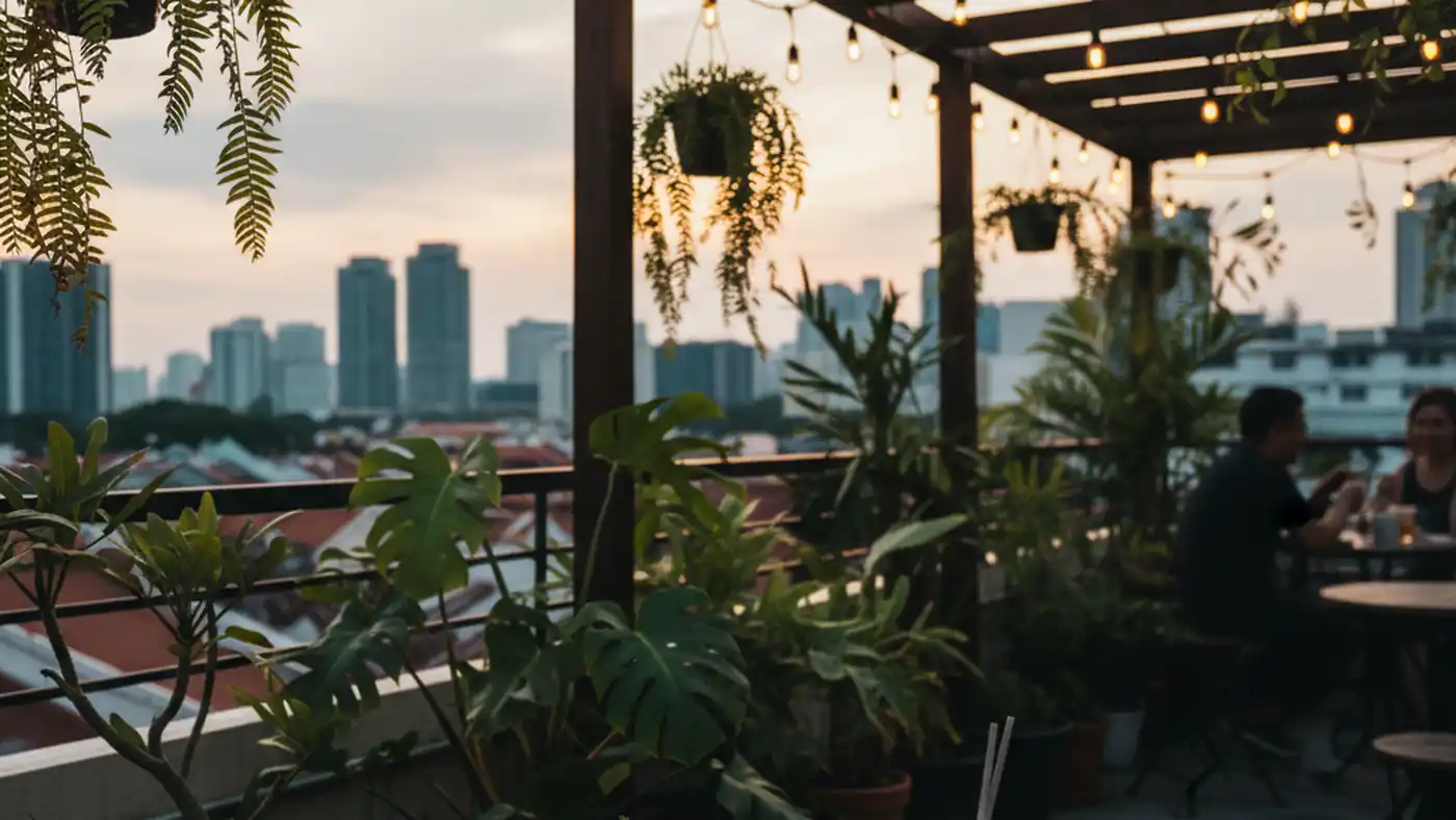Small rooftop bar in Tiong Bahru with cocktails on a table and soft skyline behind potted plants